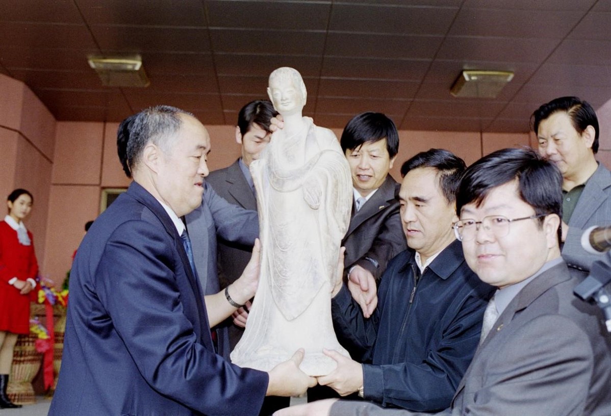 2002年10月9日博物馆开馆仪式上学校领导接受甘肃省文物局赠送的麦积山石窟第133窟小沙弥复制品
